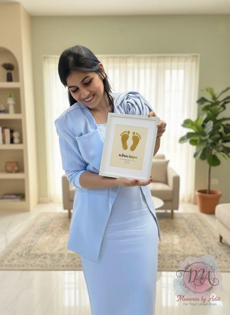 Aditi Jain, founder of Memories by Aditi, holding a gold foil footprint keepsake